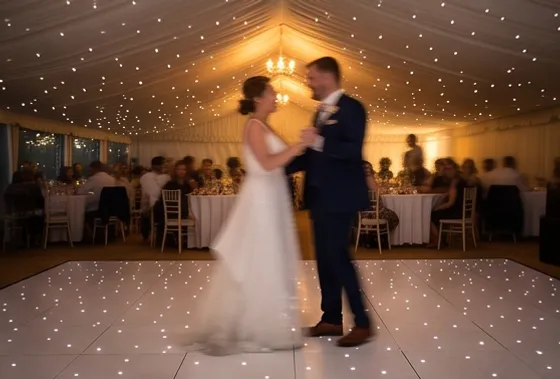 First dance on a white starlit dance floor inside a lined wedding marquee